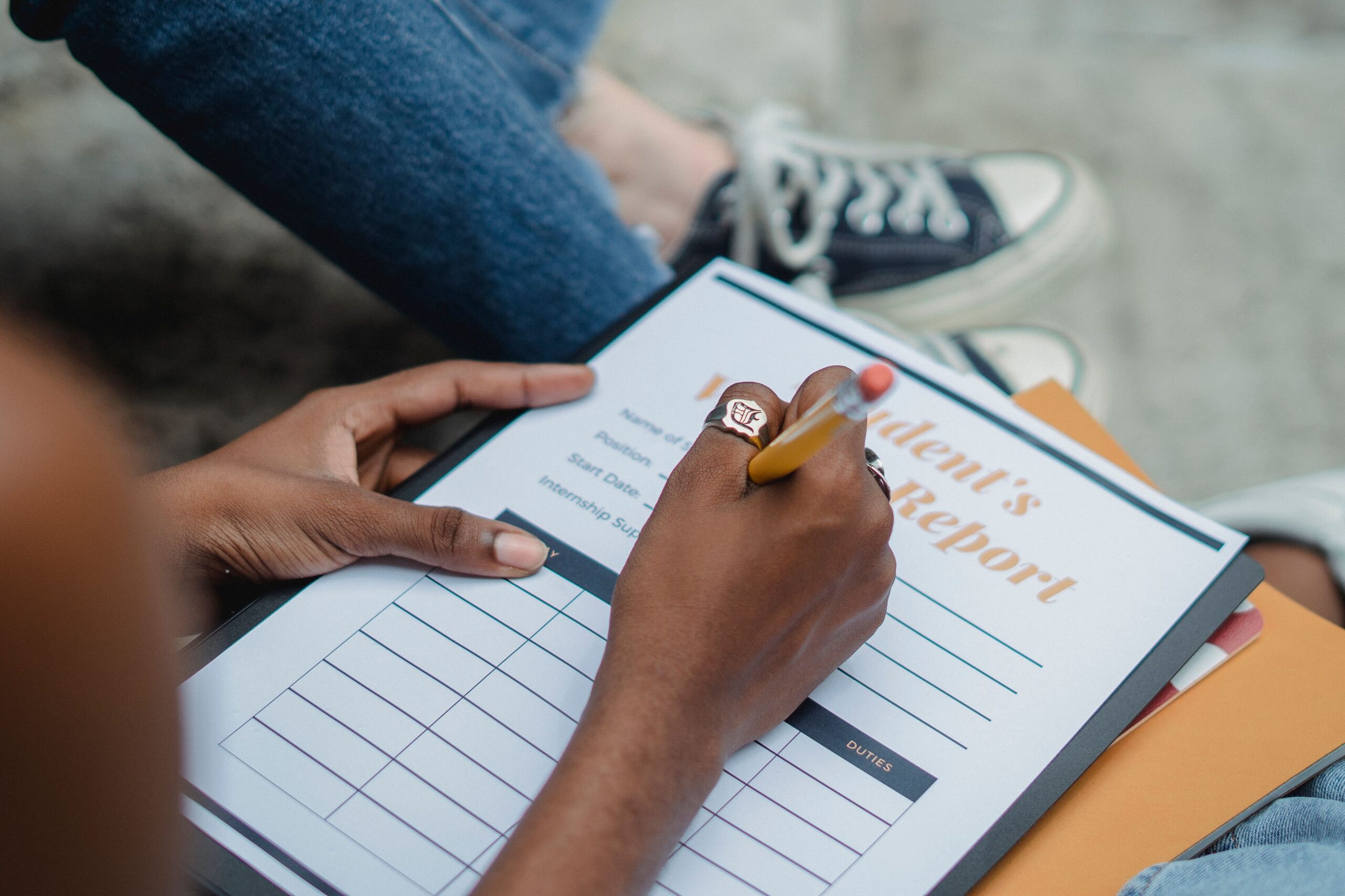 A photo of a student writing on a document titled Student Weekly Report.