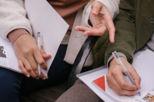 A photo of people's hands holding pens and writing.